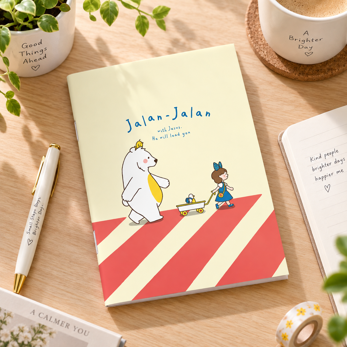 Jalan-Jalan With Jesus A6 Christian notebook styled on a bright wooden desk with stationery and a coffee cup