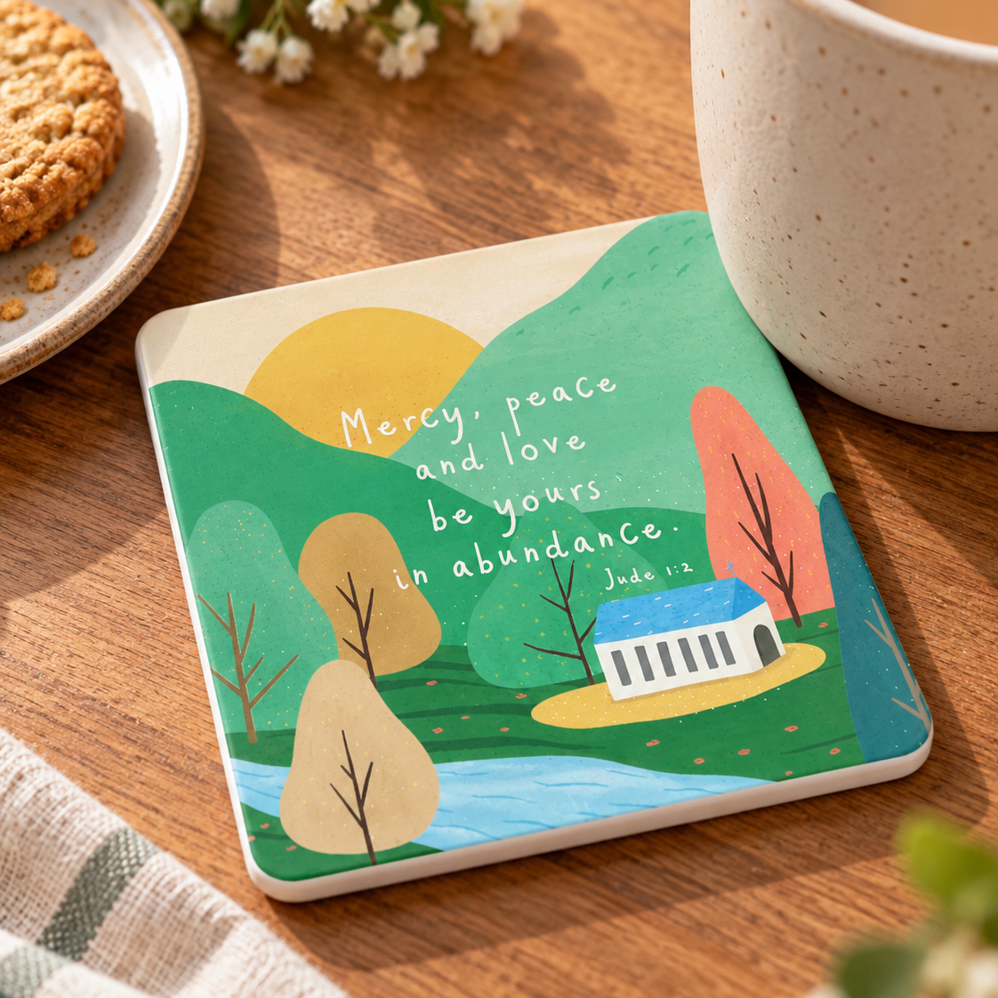 Mercy Peace and Love Jude 1:2 Christian coaster with white sides styled beside coffee on a warm wooden table