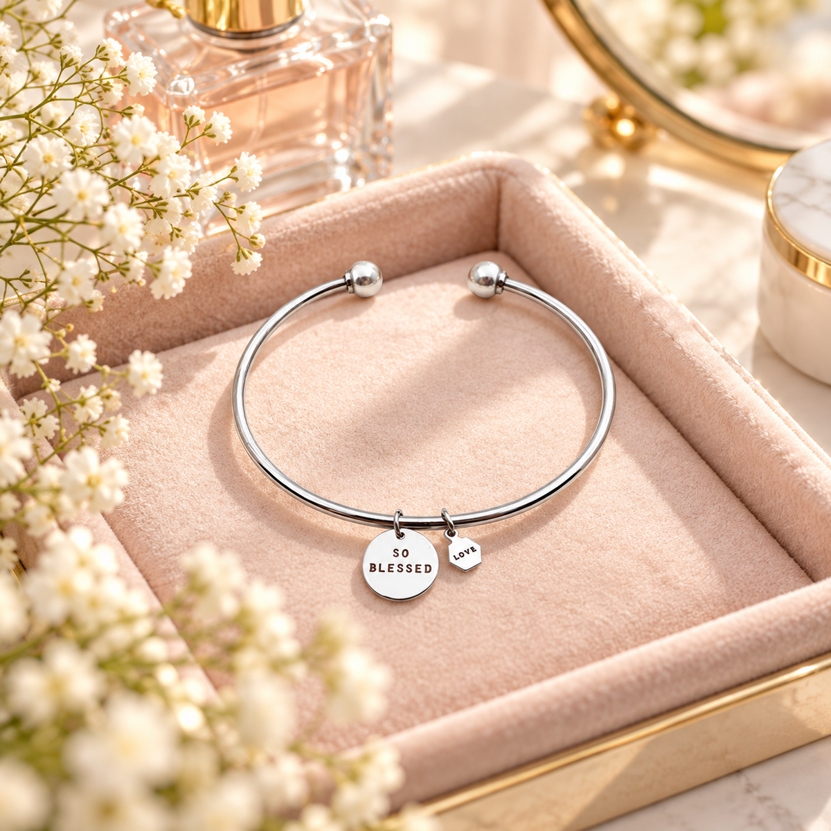 Silver round pendant Christian bracelet with So Blessed and Love charms styled in a soft pink jewellery tray with flowers