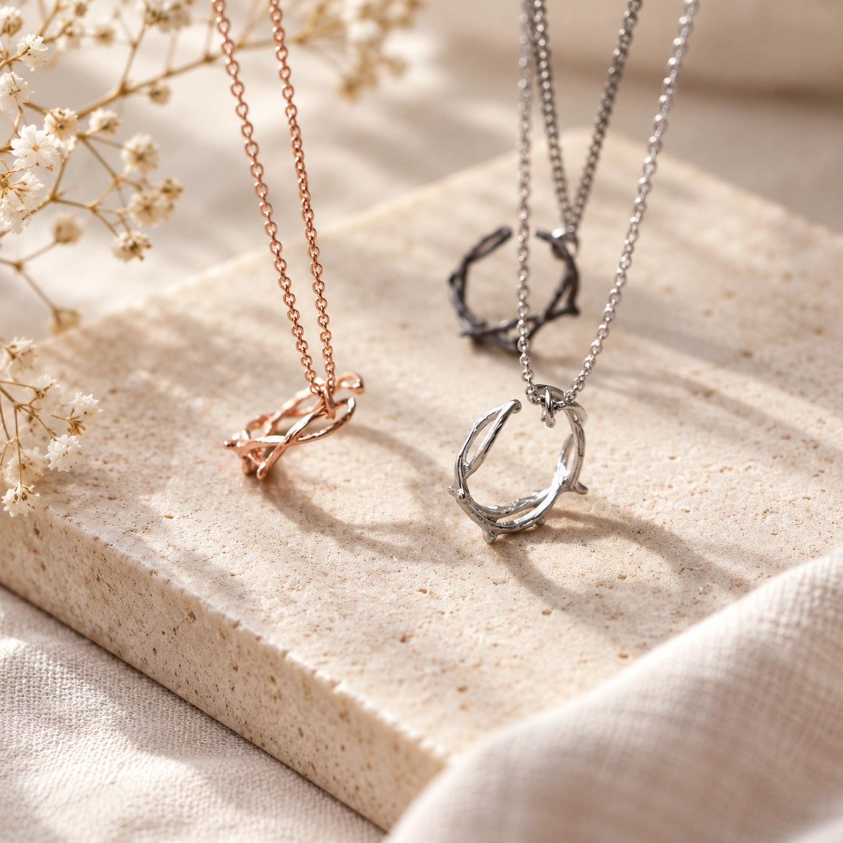 Crown of Thorns Christian necklaces in rose gold, silver and black finishes styled on a light stone surface with soft natural light