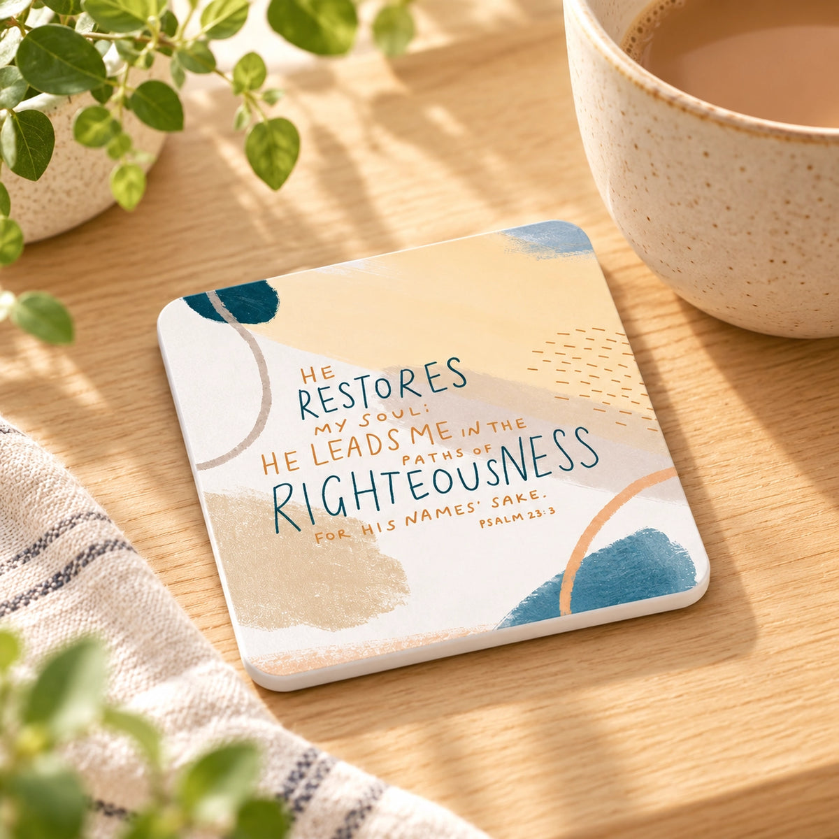 He Restores My Soul Psalm 23:3 Christian coaster beside a coffee cup in a warm sunlit setting