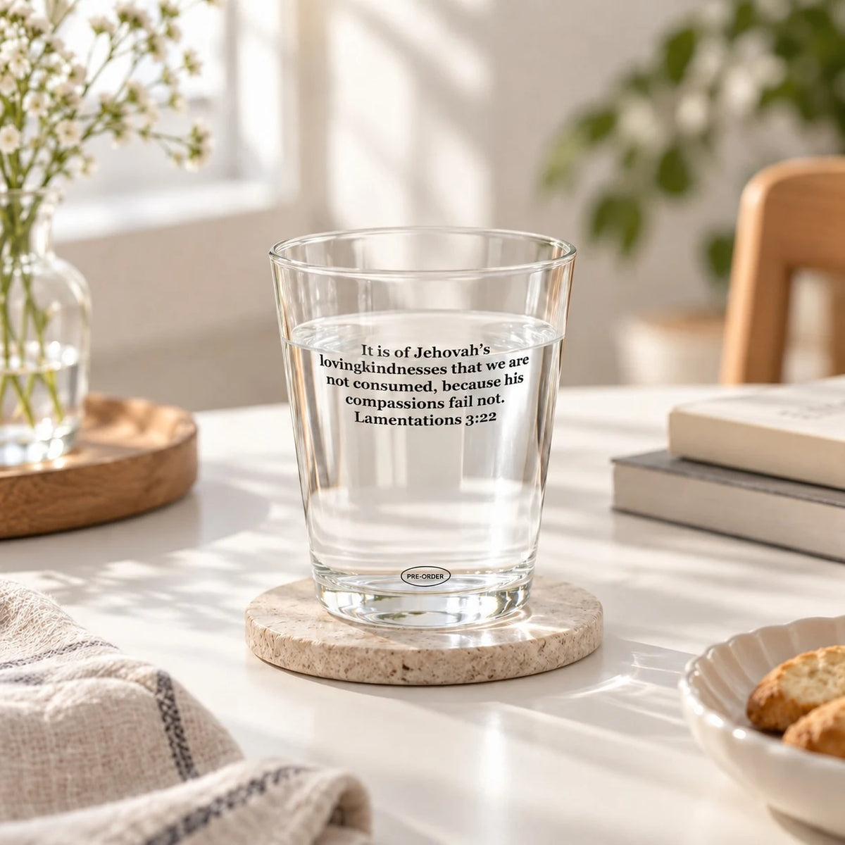 Jehovah's Lovingkindness scripture glass cup filled with water on a stone coaster in a sunlit room