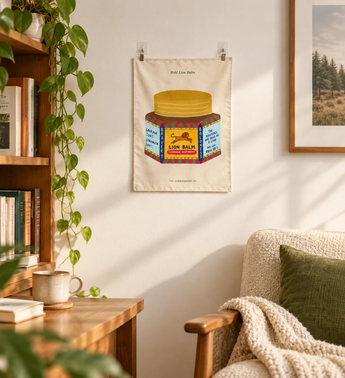 Bold Lion Balm small wall tapestry hanging in a cosy reading corner with books, trailing houseplant and armchair