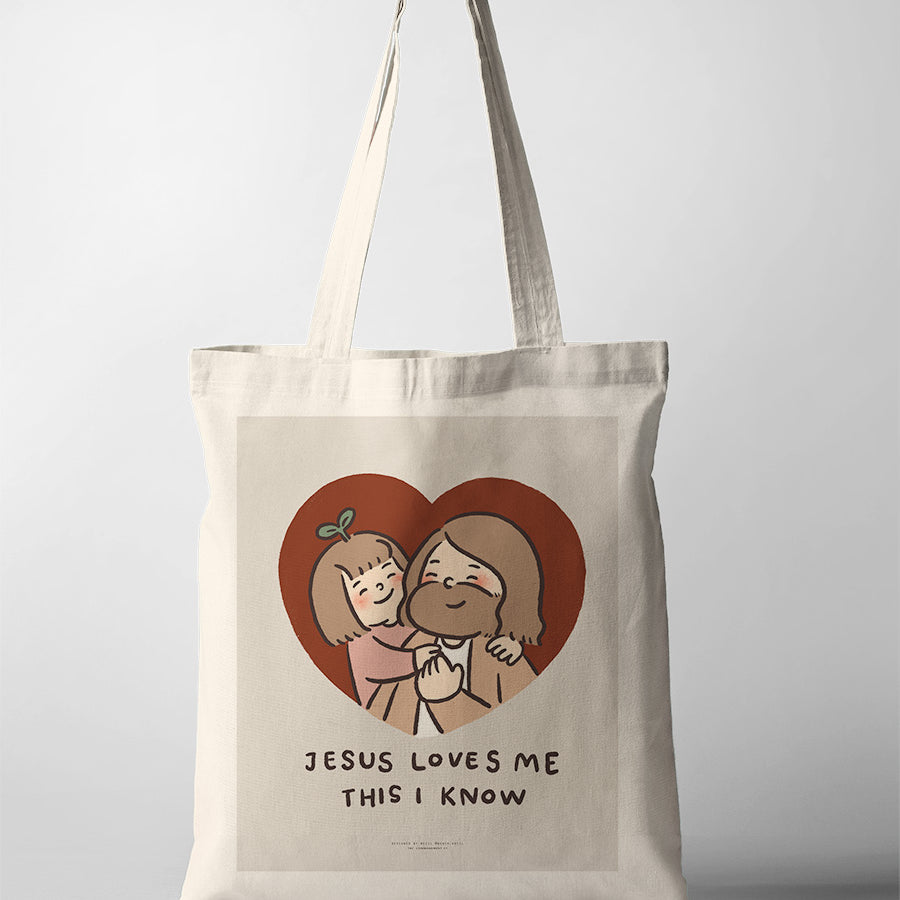 Canvas tote bag featuring a heartwarming illustration of Jesus embracing a joyful child, with the text 'Jesus Loves Me This I Know' as a message of love and faith.