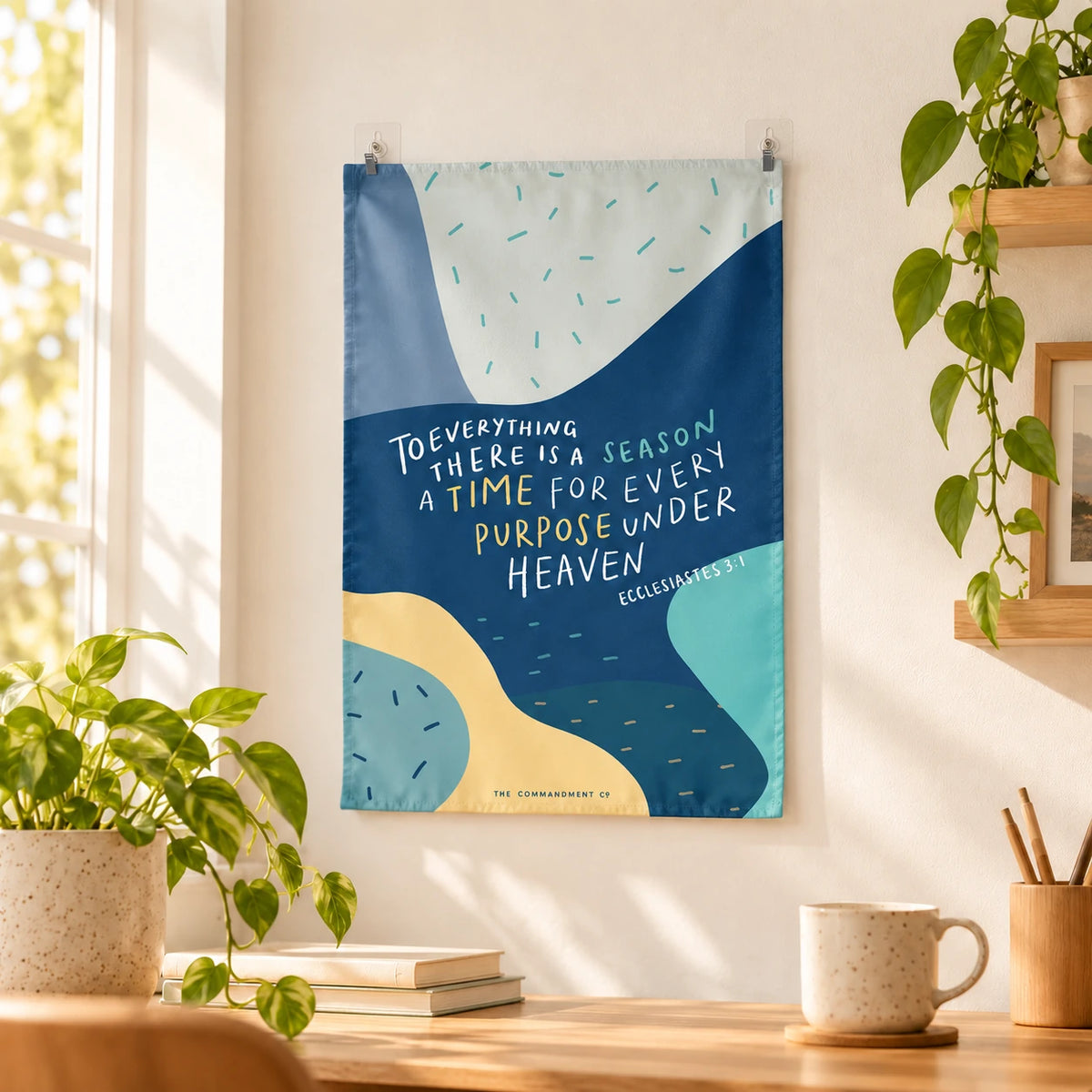 A Time For Every Purpose small wall tapestry hanging by two adhesive wall clips above a desk