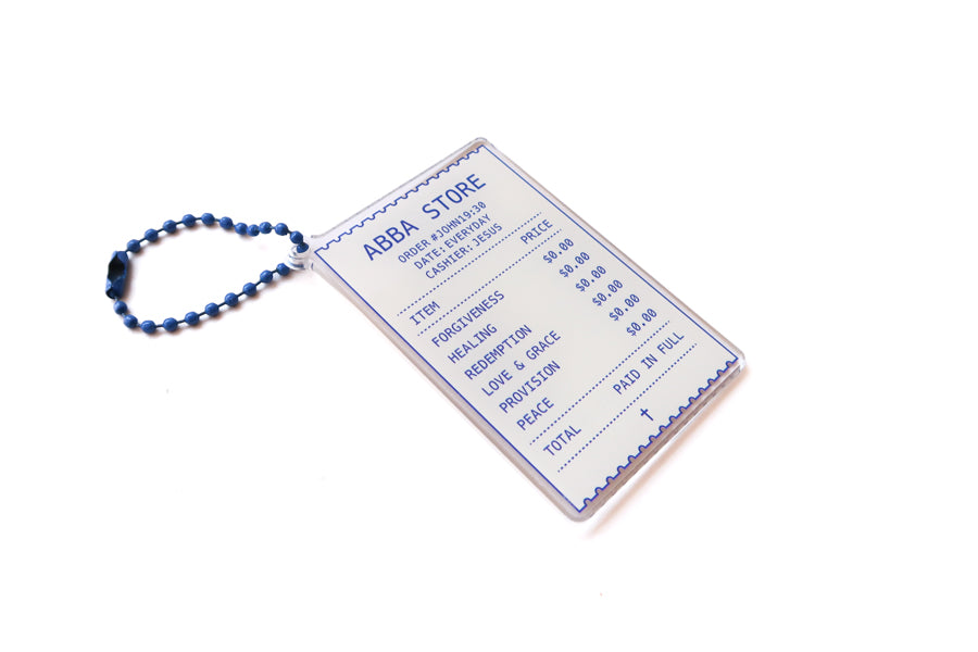 Angled view of Abba Store receipt-inspired Christian acrylic keychain with blue ball chain and Paid in Full design