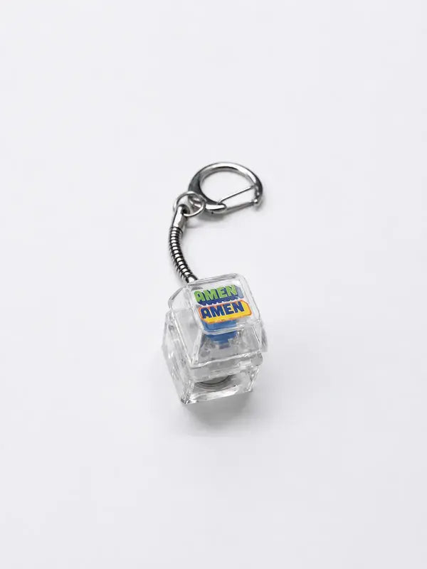 AMEN AMEN light-up Christian keycap keychain with clear body and silver clasp on a light grey background