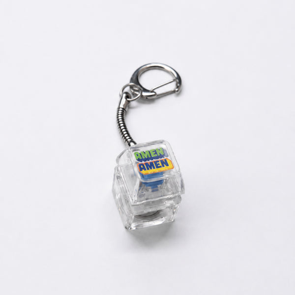 AMEN AMEN press-on light-up keycap keychain with clear casing and silver clasp on a white background