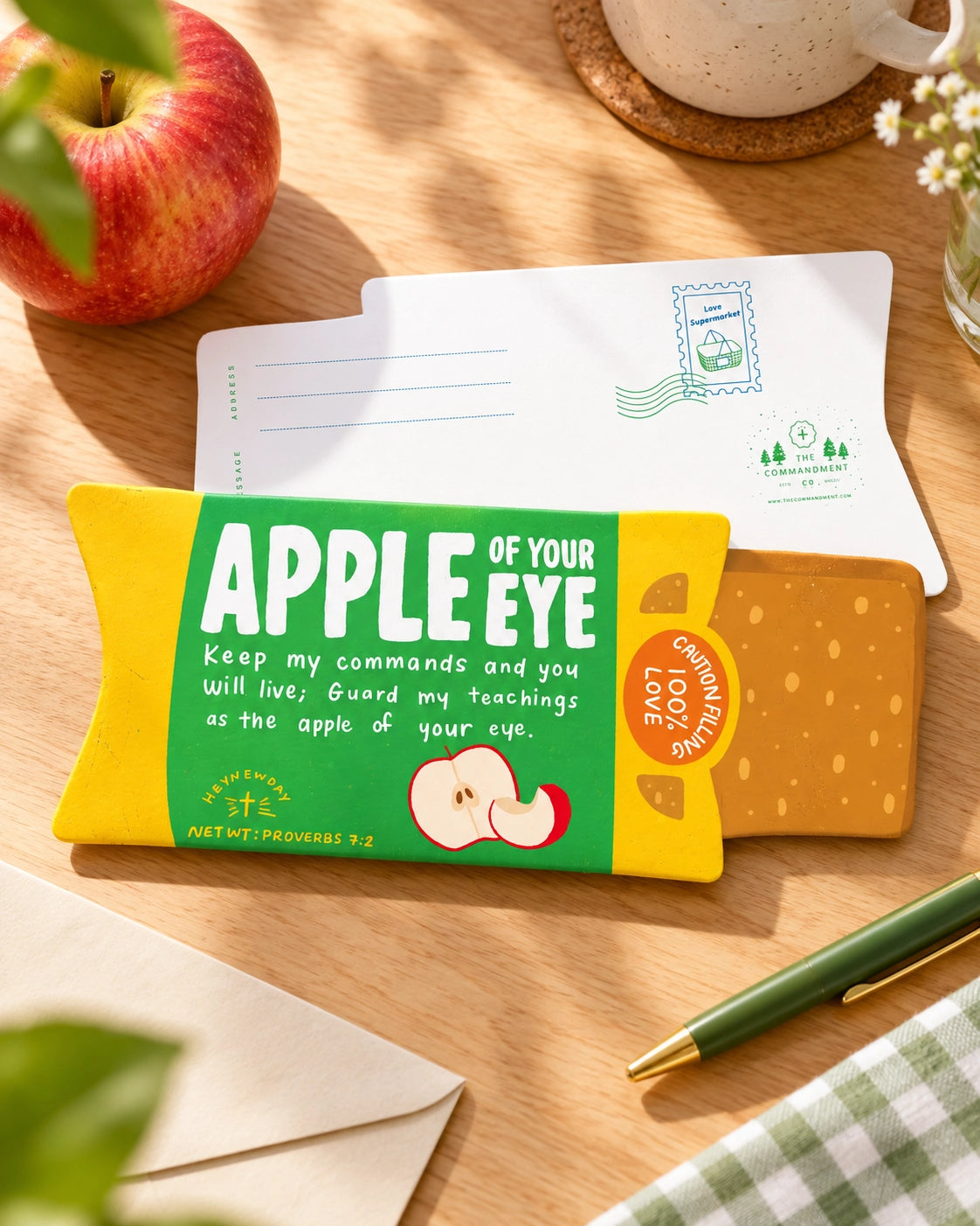 Apple of Your Pie LOVE SUPERMARKET Christian card styled on a sunny wooden desk with an apple and stationery.