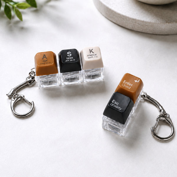 ASK SEEK KNOCK and Enter Christ Esc Anxiety light-up keycap keychains arranged on a white tabletop