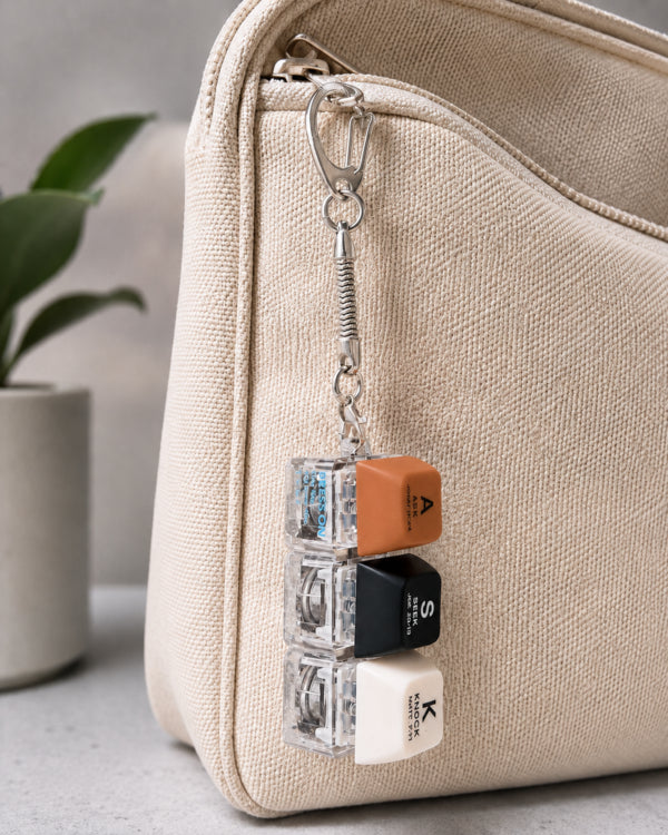 ASK SEEK KNOCK light-up keycap keychain clipped to a textured beige bag