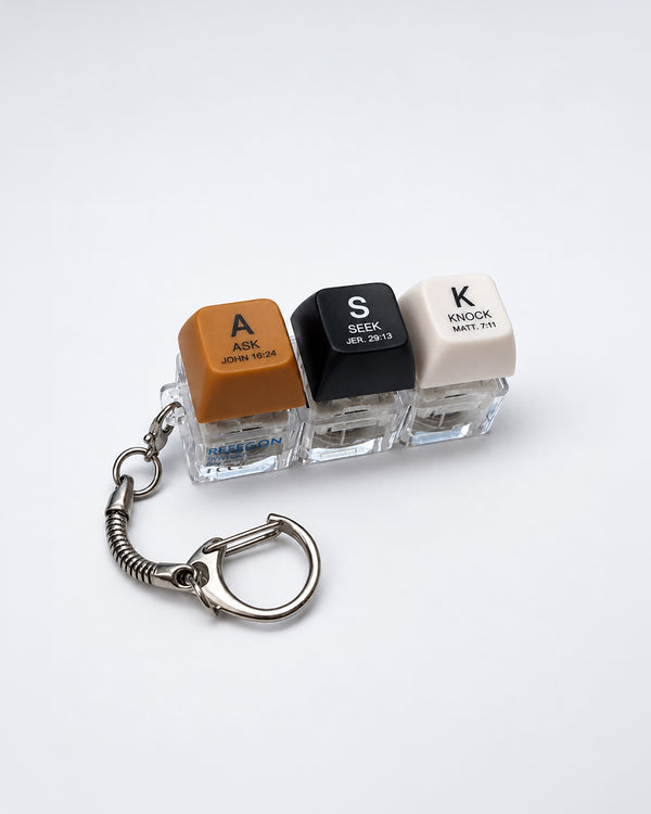 ASK SEEK KNOCK light-up keycap keychain with three coloured keys and silver clasp on a white background
