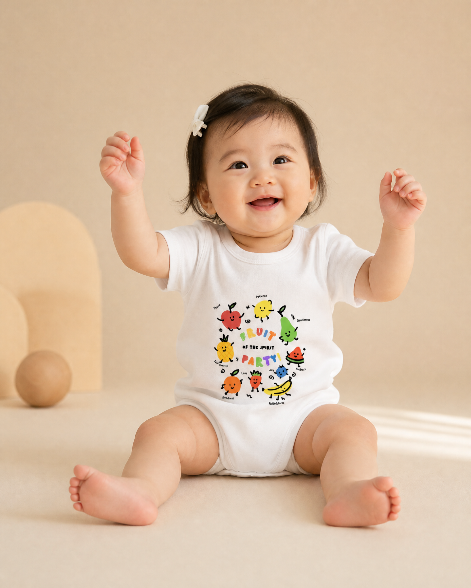 Baby wearing a white Fruit of the Spirit Party romper with colourful fruit illustrations