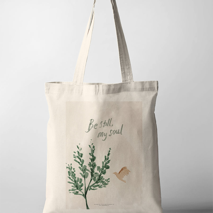 Christian tote bag featuring “Be Still, My Soul” with green botanical artwork and a flying bird illustration