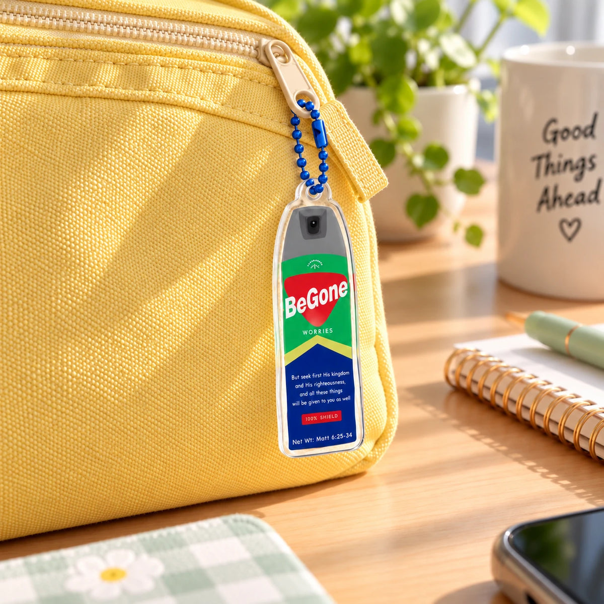 BeGone Worries insect repellent acrylic keychain on blue ball chain attached to the zipper pull of a yellow canvas pencil case.