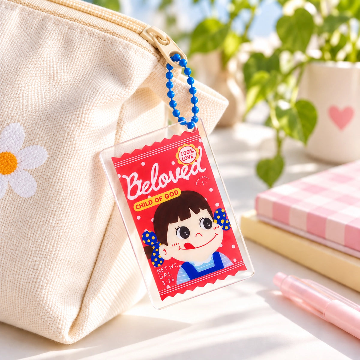 Beloved Milk Candy Girl acrylic keychain attached through a zipper pull on a cream canvas pouch in bright natural light