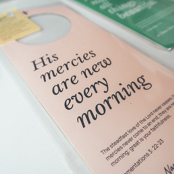 Close-up view of a pink Christian door hanger featuring the Bible verse 'His mercies are new every morning' from Lamentations 3:22-23, emphasizing faith and hope.