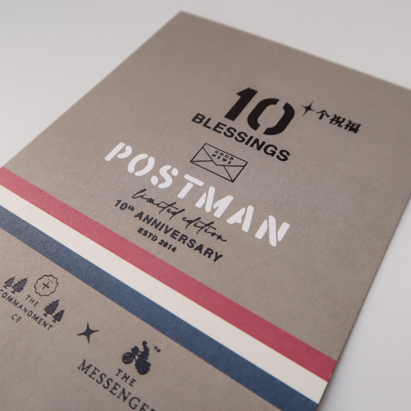 A detailed view of the "10 Blessings Postman" limited edition 10th-anniversary design, featuring bold typography, accent stripes in red, white, and blue, and logos from The Commandment Co. and The Messenger.