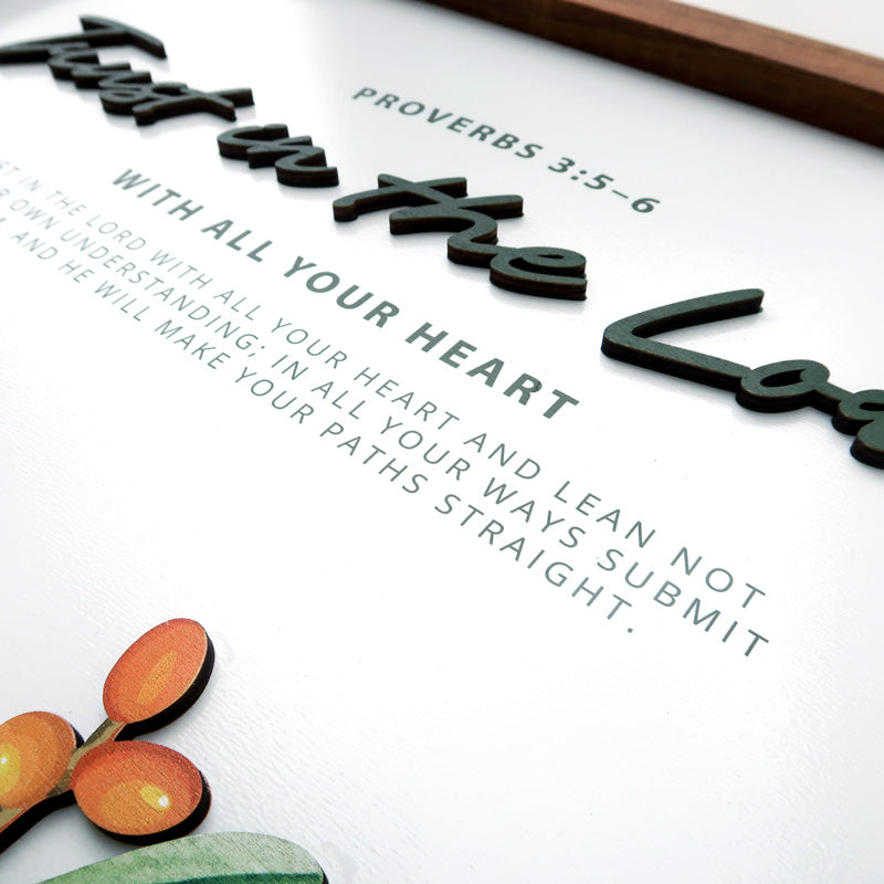 Close-up of a handcrafted wooden scripture poster featuring the Bible verse Proverbs 3:5-6, "Trust in the Lord with all your heart," with layered 3D text and vibrant accents.