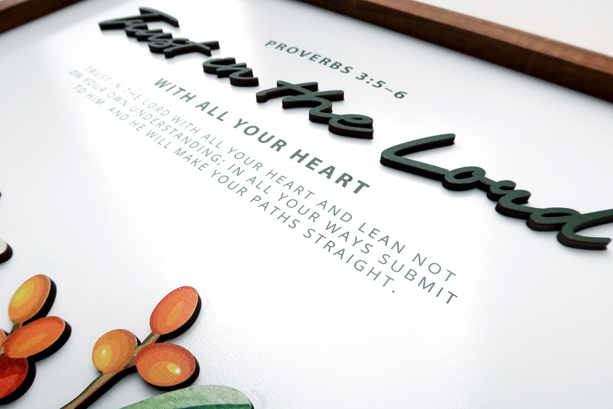 Close-up of a handcrafted wooden scripture poster featuring the Bible verse Proverbs 3:5-6, "Trust in the Lord with all your heart," with layered 3D text and vibrant accents.