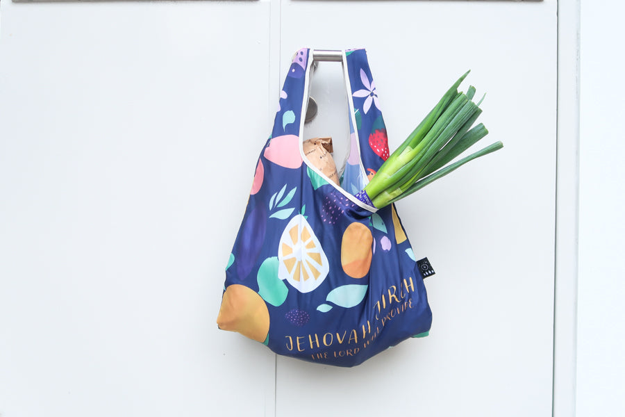 Foldable reusable
shopping bag with phrase
“Jehovah Jireh” and
colorful fruit design,
perfect for Christian gifts
from a Christian gift store.