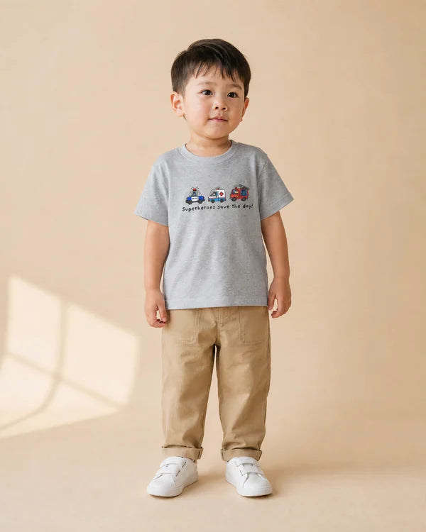 Young child wearing the grey Superheroes Save the Day kids T-shirt with beige trousers