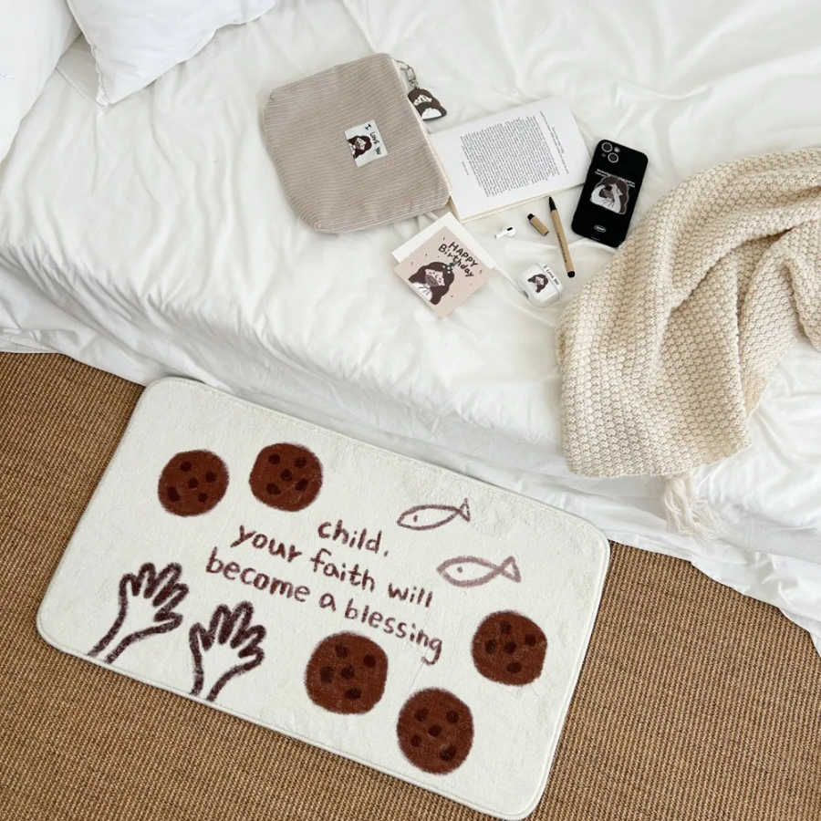 Cream rug with playful illustrations of loaves, fish, and hands, featuring the message "Child, your faith will become a blessing," placed beside a cozy bed, inspiring faith and simple happiness in a Christian home from Jincha God.