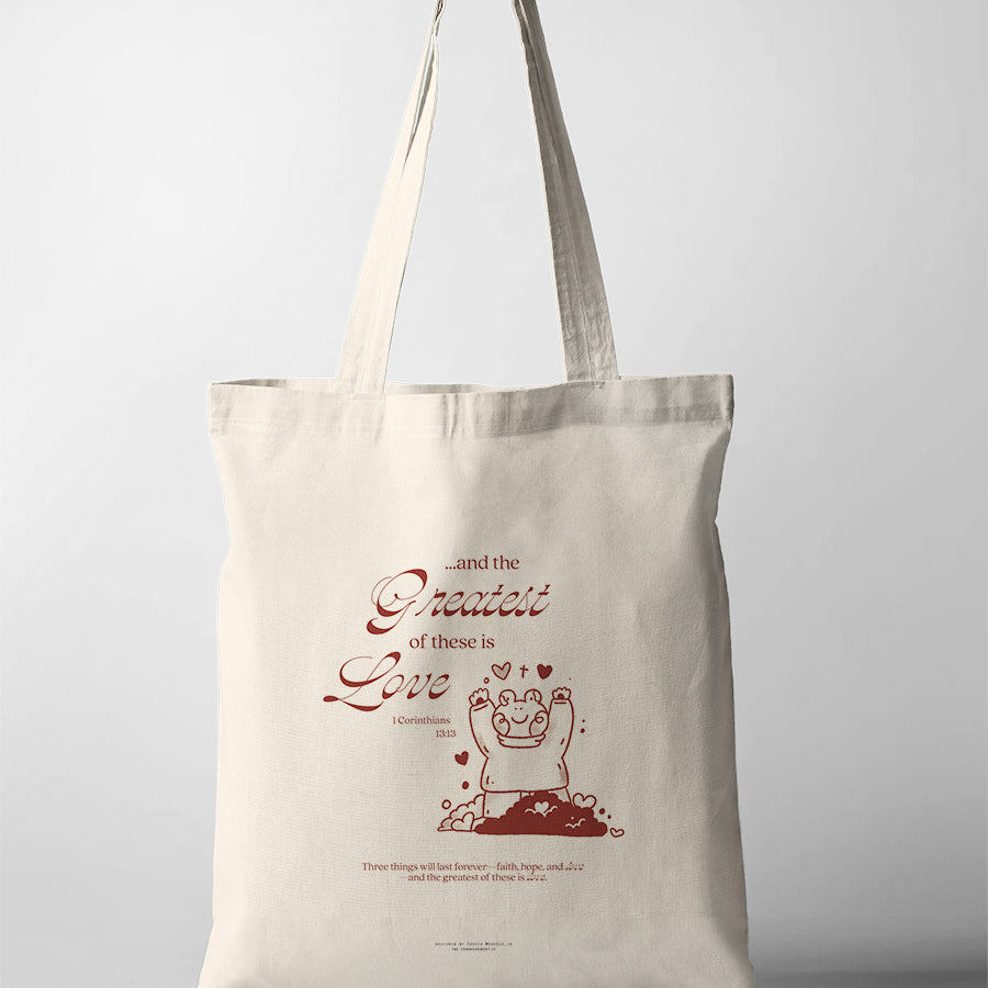 Natural canvas Christian tote bag featuring a joyful bear illustration and The Greatest of These Is Love from 1 Corinthians 13:13.