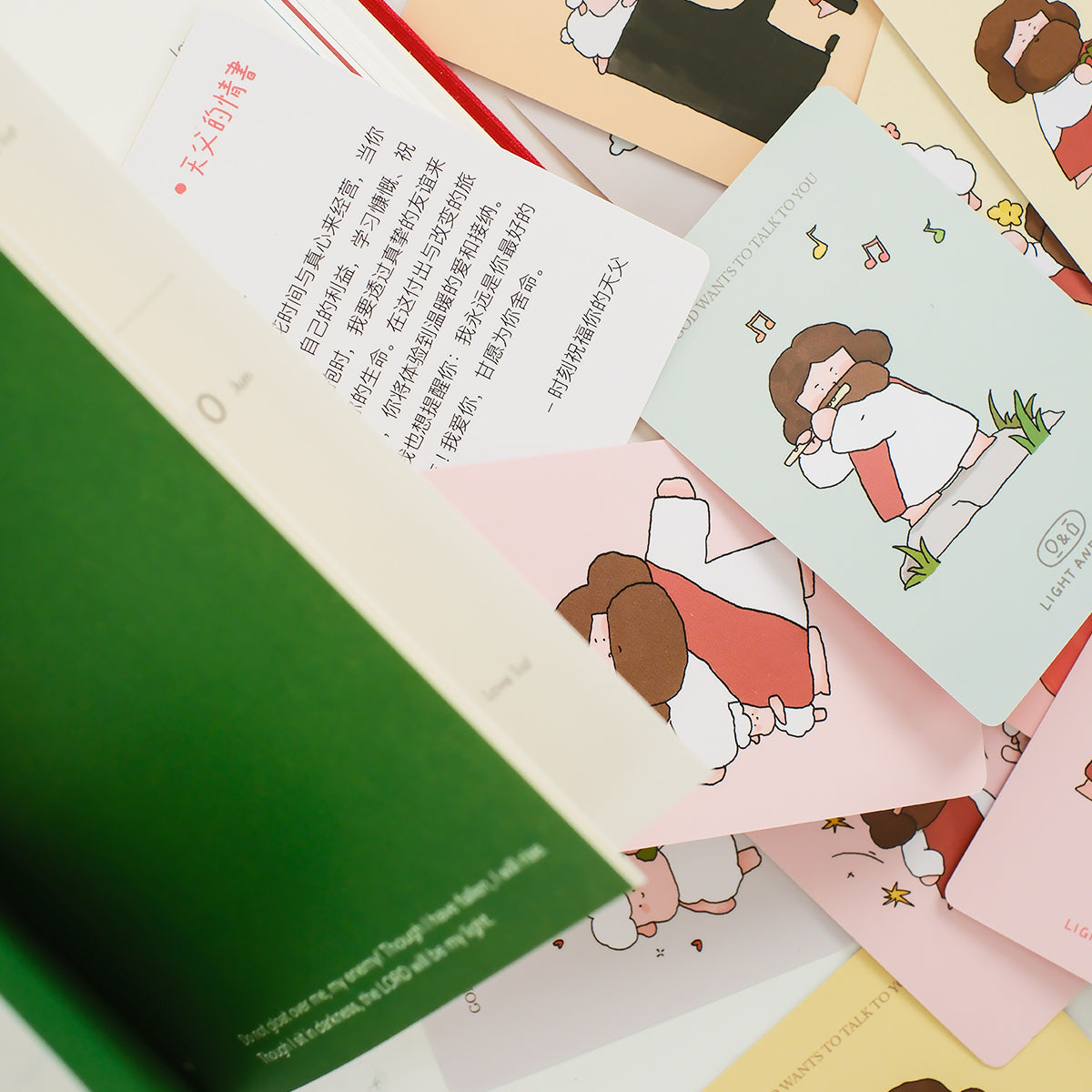 Christian mini encouragement cards beside an open book showing illustrated Jesus designs and faith-based messages in soft pastel tones