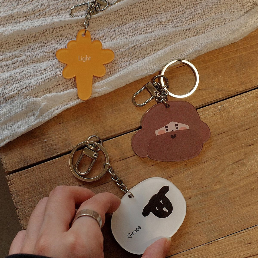 Collection of Christian keychains with designs like "Light" and "Grace," displayed on a wooden surface, symbolizing faith and inspiration.