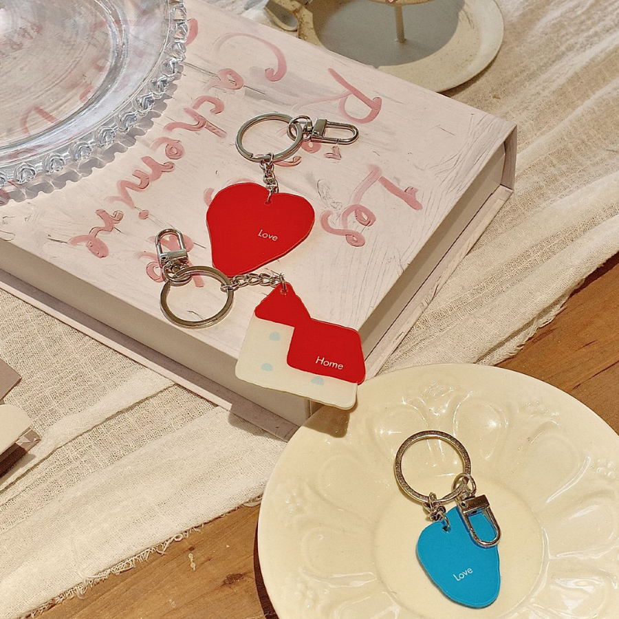 Christian keychains with "Love" and "Home" designs displayed on a book and plate, symbolizing faith and warmth.