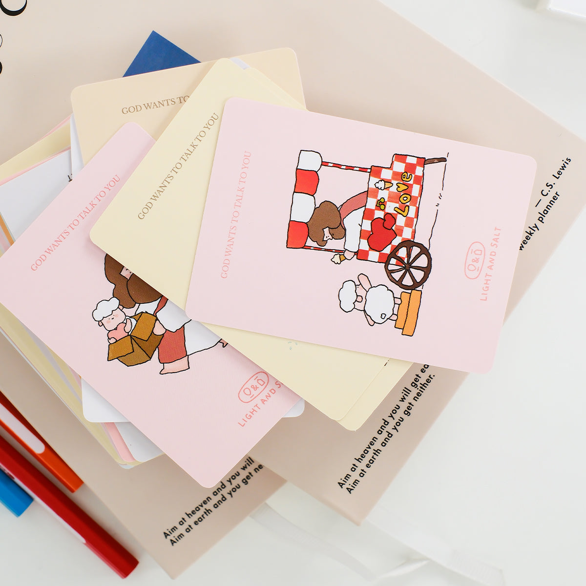 Stack of Christian mini cards with cute Jesus illustrations placed with stationery items, ideal as small faith-based gifts or encouragement notes