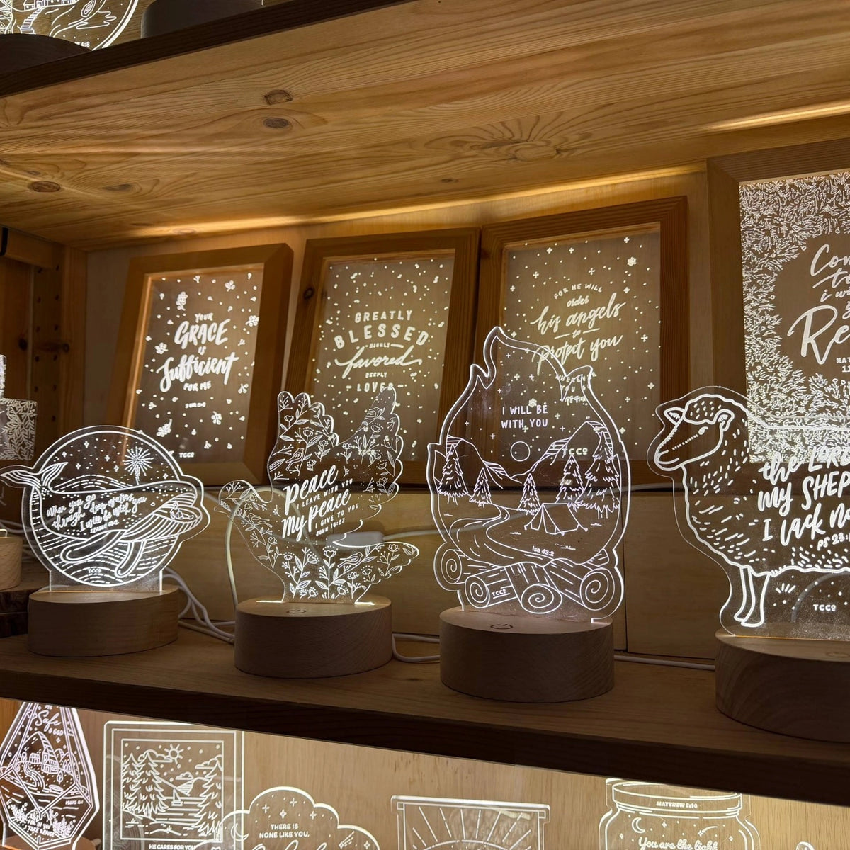 Glowing Christian night lights arranged on a wooden display shelf at The Commandment Co