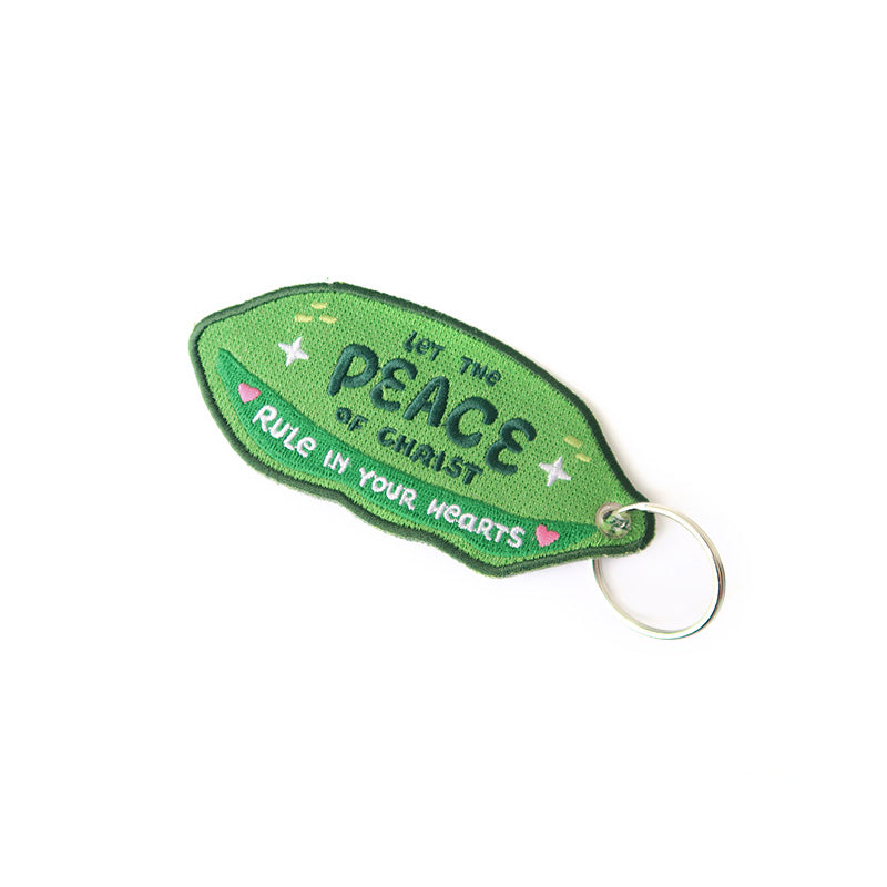 Backside of the green 'Peas Be With You' keychain with motivational text.
