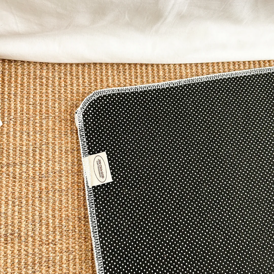 Cream rug with the words "We love, because he first loved us. 1 John 4:19" placed on a mat by white curtains, bringing faith and simple happiness to any Christian home from Jincha God.