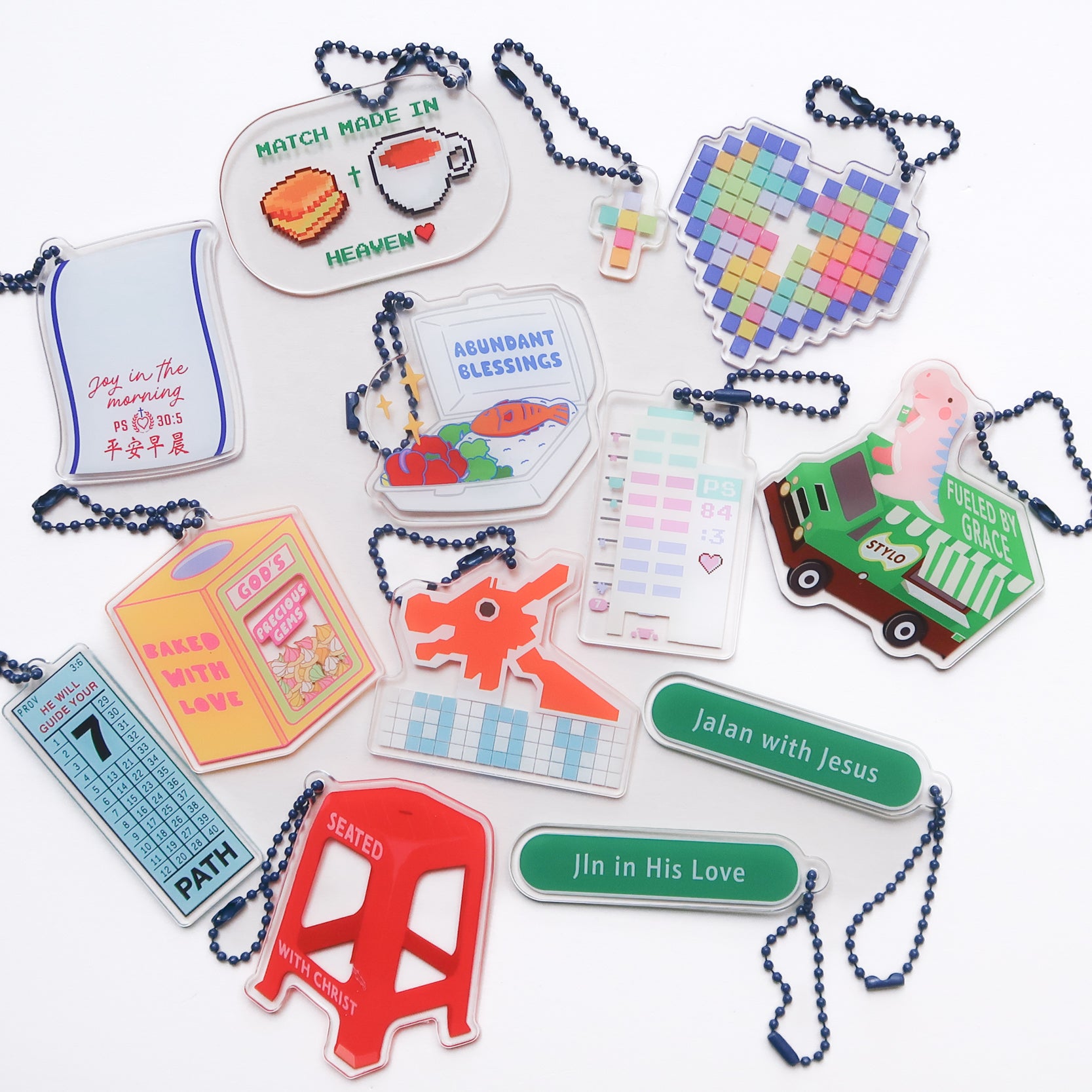 Collection of colorful acrylic keychains with Christian themes and designs, including Bible verses and inspirational messages, from The Commandment Co, Singapore.
