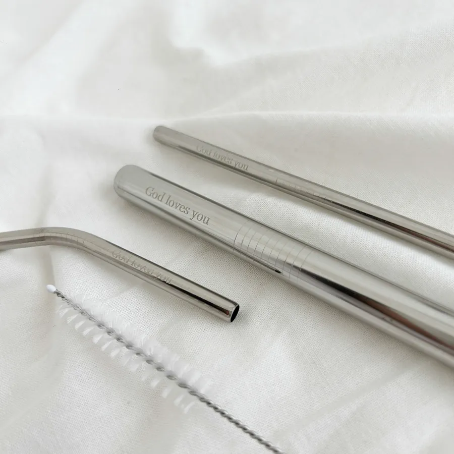 Close-up of stainless steel straws engraved with the message "God loves you," showcasing the elegant design and included cleaning brush