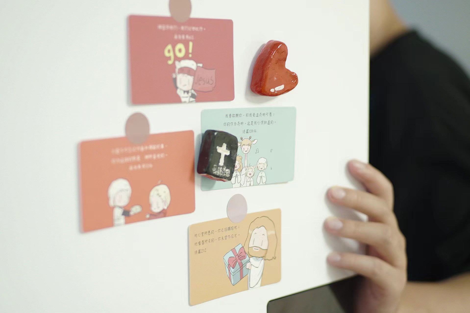 Religious scripture cards with cute drawings attached to a whiteboard using heart and cross-shaped magnets