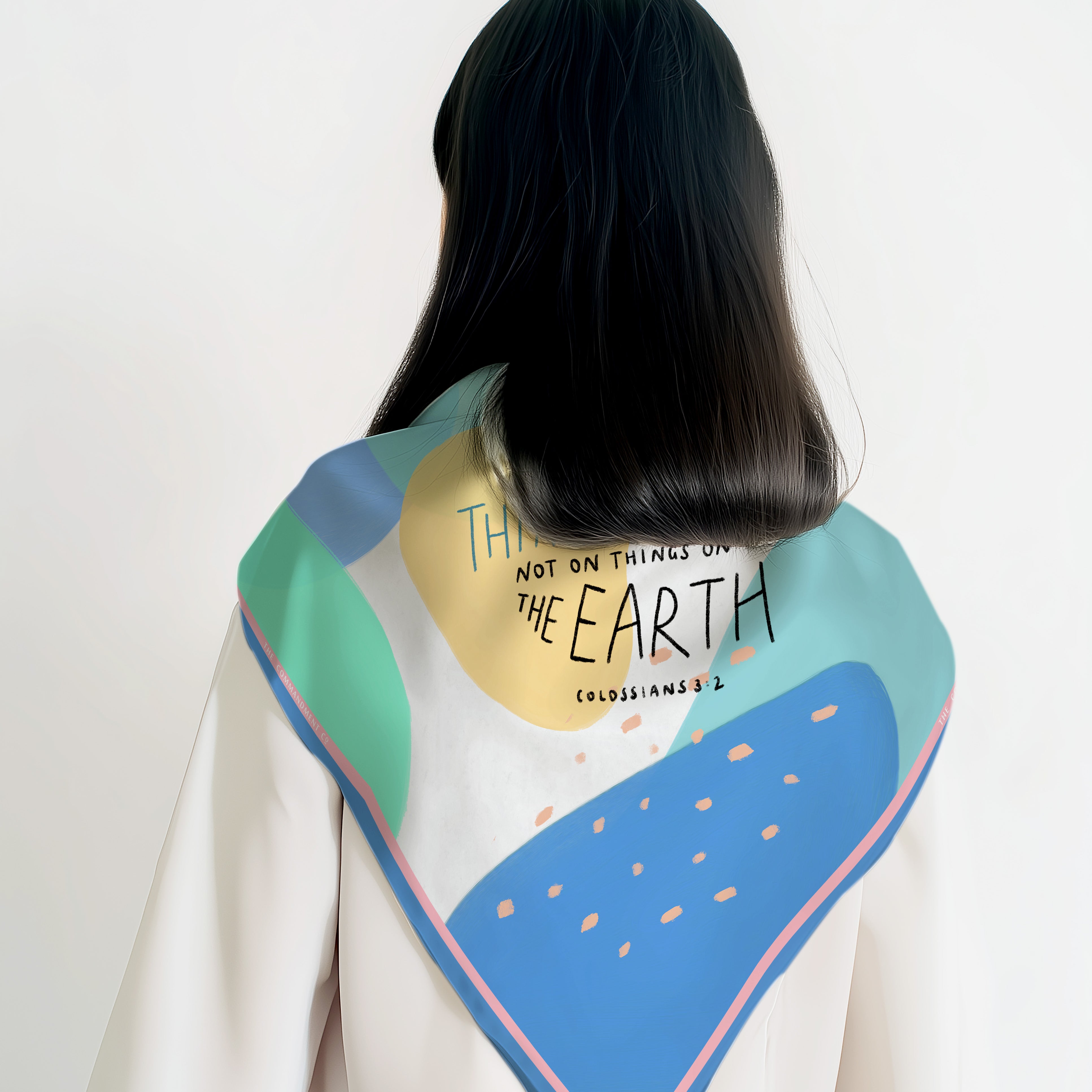 Back view of a model wearing a colorful abstract scarf featuring Colossians 3:2 “Set your mind on things above” in a modern Christian design by The Commandment Co.