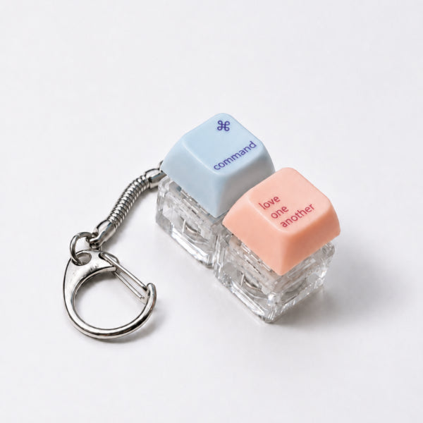Command Love One Another double light-up keycap keychain in blue and peach on a white background