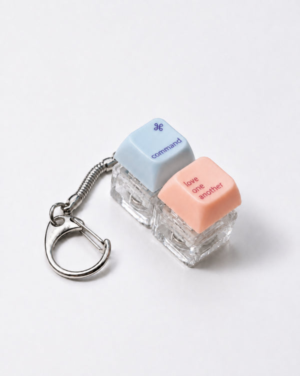 Command Love One Another double light-up keycap keychain in blue and peach on a white background
