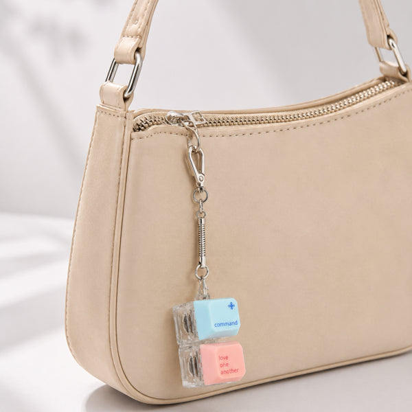 Command Love One Another double keycap keychain clipped to a beige handbag