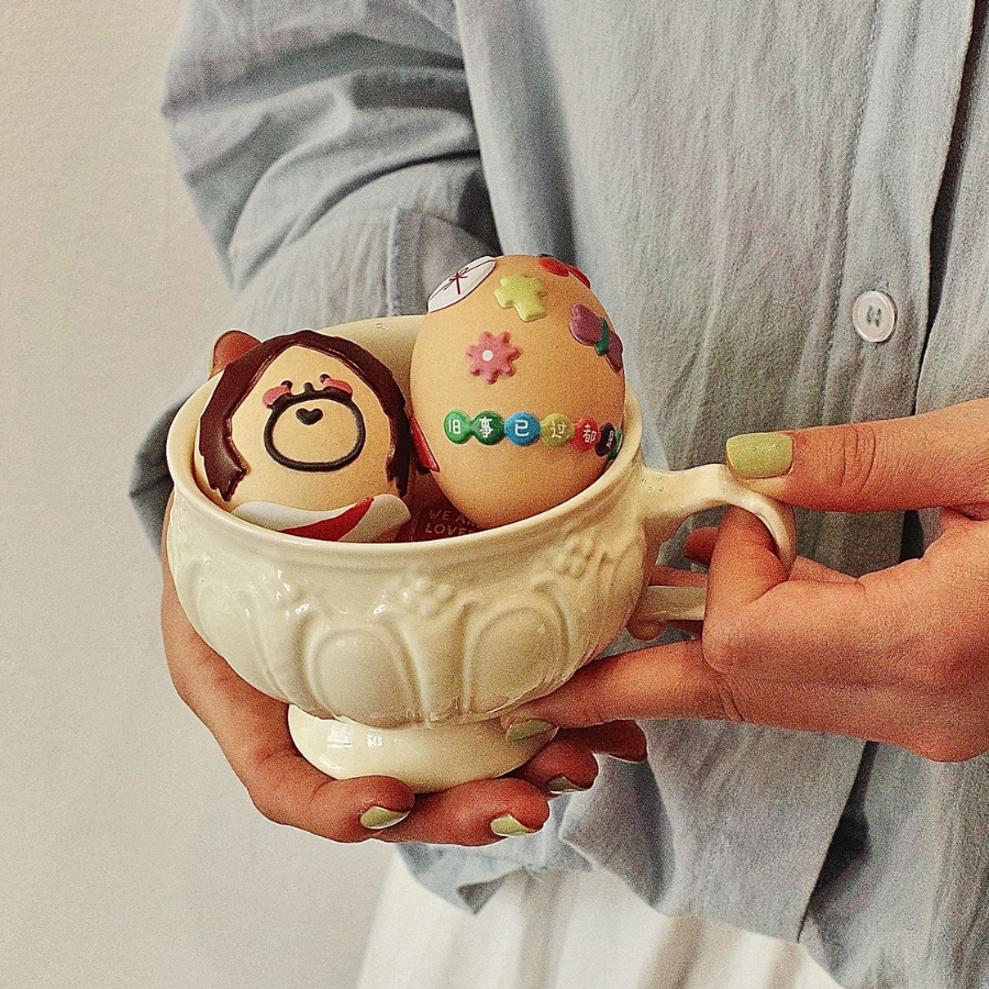 Two eggs in a cup decorated with Soft Jesus stickers, featuring playful and colorful designs.