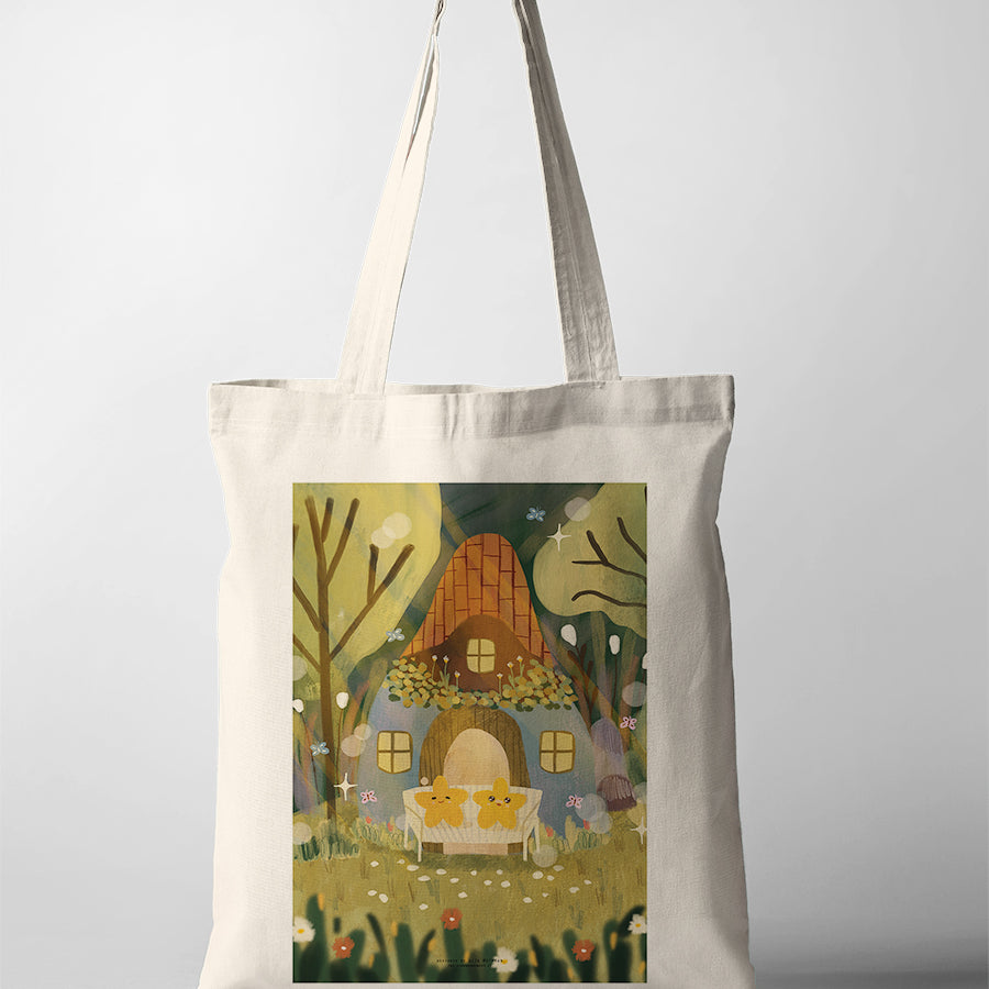 Canvas tote bag with Dita illustration of a cozy cottage house surrounded by trees and flowers in a warm, whimsical setting