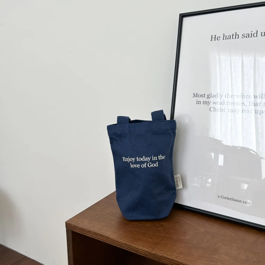 Navy blue beverage bag with the uplifting message "Enjoy today in the love of God," paired with a white pouch and inspirational card, reflecting faith, encouragement, and simple happiness.