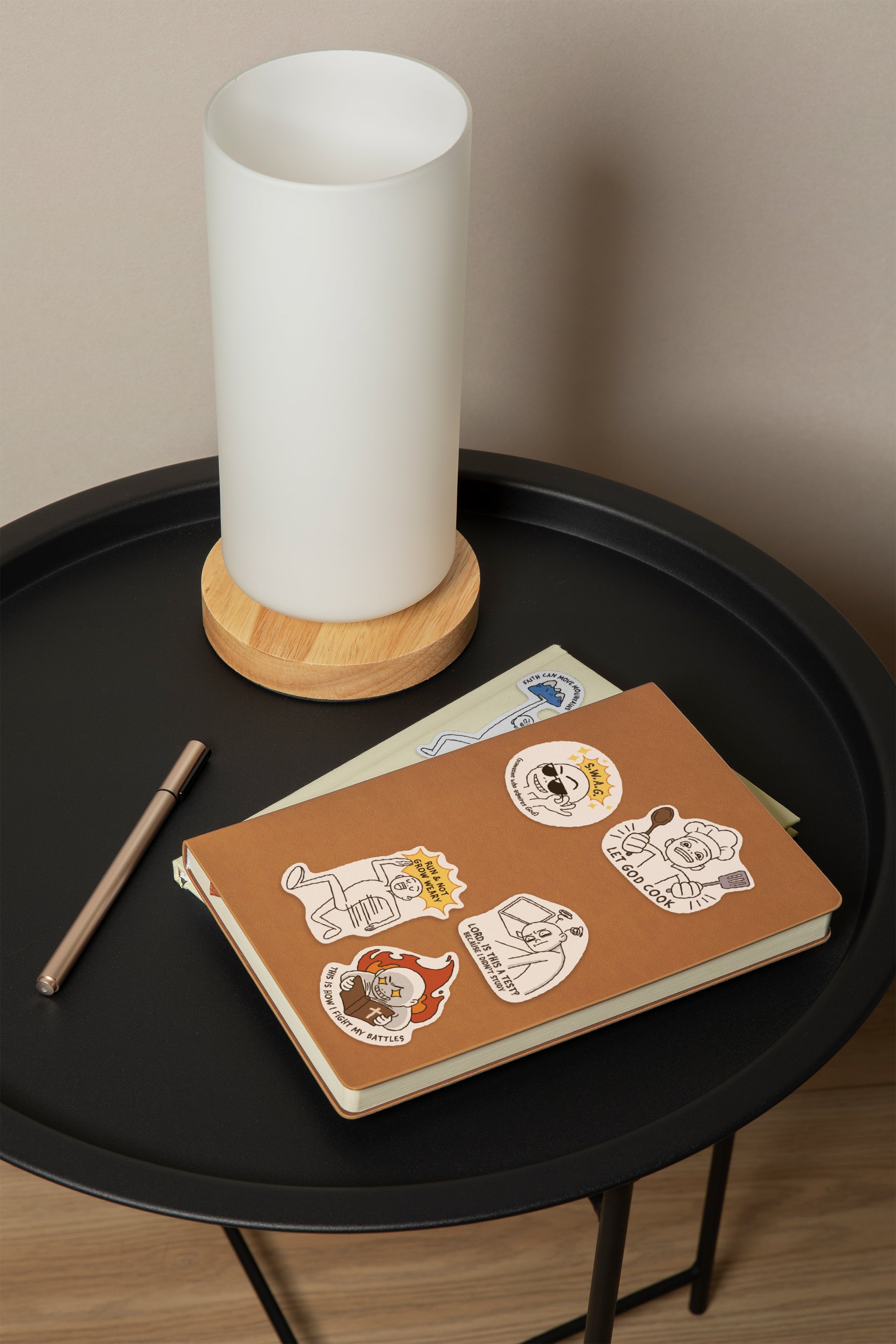 Notebook decorated with Everyday Believer stickers featuring Christian messages like "Let God Cook" and "Run & Not Grow Weary," from The Commandment Co, Singapore.