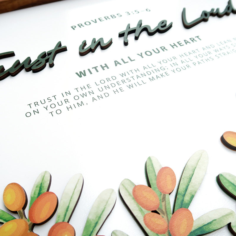 Close-up of a wooden board poster featuring the scripture "Trust in the Lord with all your heart" from Proverbs 3:5-6. The design includes layered text and decorative orange berries with green leaves.