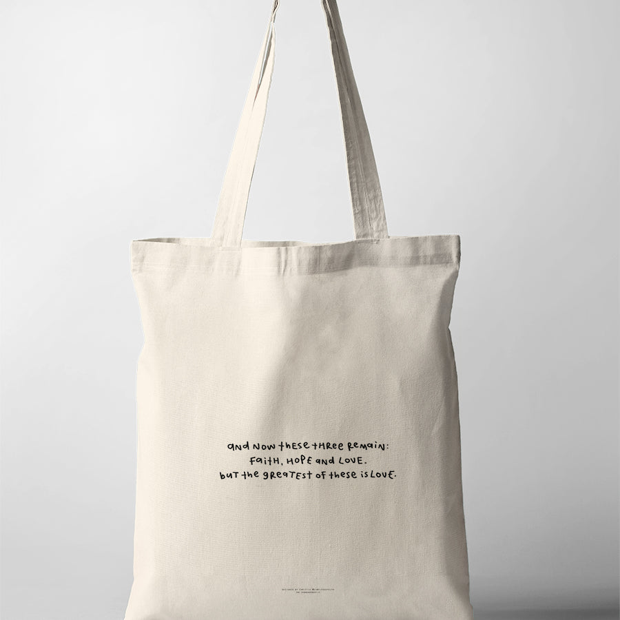 Faith Hope Love Bible verse tote bag featuring 1 Corinthians 13:13 in a simple handwritten style on a natural canvas tote.