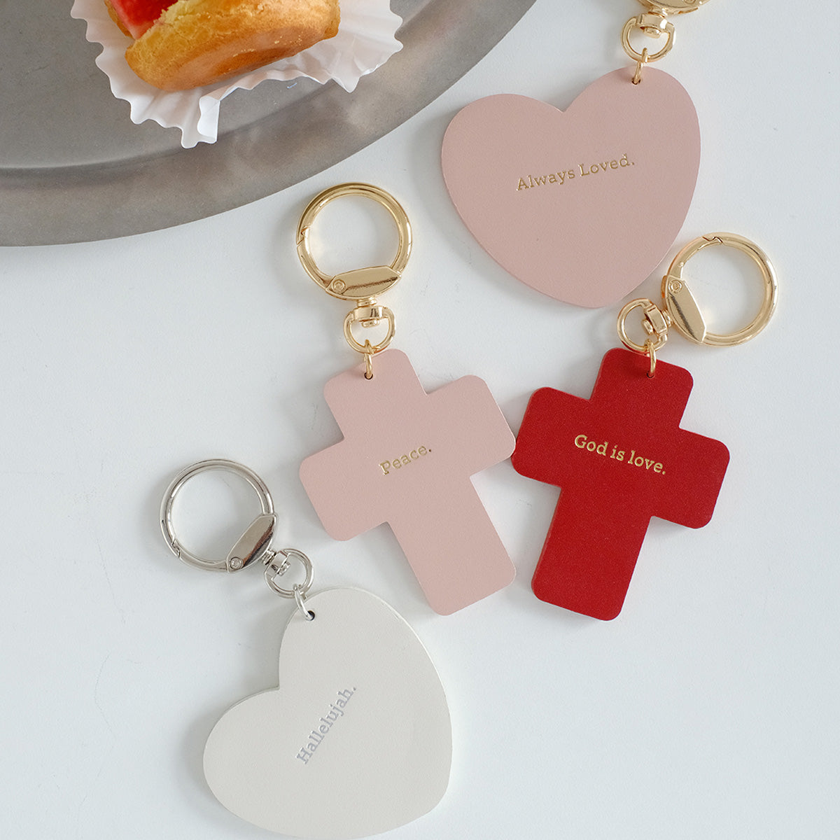 Faith-inspired keychains featuring cross and heart designs with engraved messages like 'God is love,' 'Peace,' and 'Hallelujah.' Perfect for gifting.