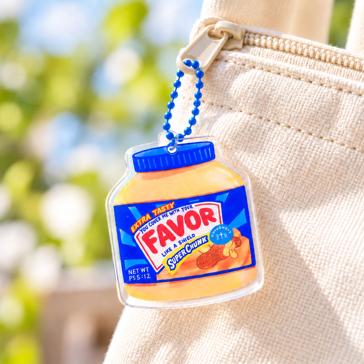 Favor Peanut Butter acrylic keychain hanging from a cream canvas bag in a bright lifestyle setting.